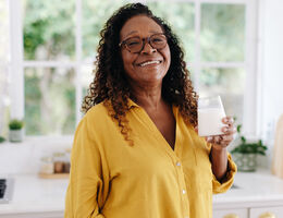 An older woman holding a glass of milk.